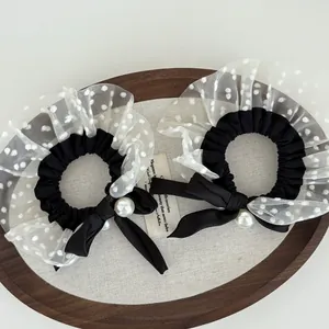 Close-up of black retro scrunchies with white polka dot lace, bow and pearl charms
