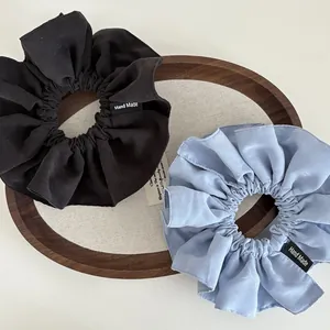 Detail of black and blue cotton scrunchies with Hand Made label on wooden tray