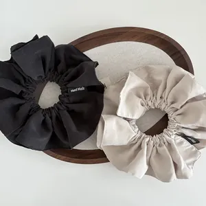 Close-up of black and beige fabric scrunchies set with Hand Made woven labels