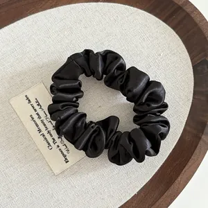 Classic black satin scrunchie with soft pleated texture and high elastic hair tie