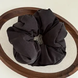 Minimalist matte carbon black oversized scrunchie placed on a wooden display tray