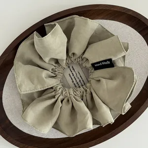 Sage green fabric scrunchie with a Hand Made label on a wooden display tray