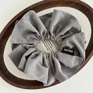Grey handmade fabric scrunchie with white stitching and signature Hand Made label