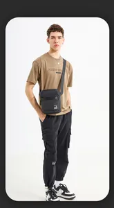 Detail of a men's trendy black nylon crossbody bag paired with a khaki textured t-shirt