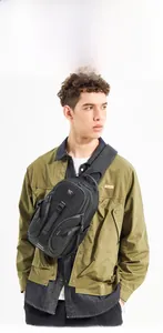 Close-up of black tactical chest bag with adjustable buckles on male model jacket