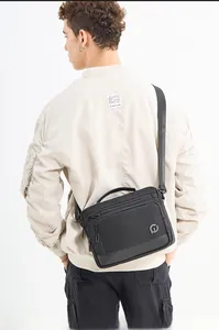 Detailed view of the large capacity black nylon crossbody bag on a male model