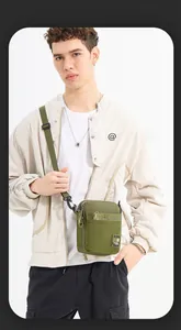 Detail of olive green nylon crossbody bag with multi-zipper pockets and woven strap