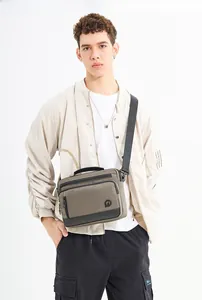 Detail of khaki and black canvas crossbody bag featuring adjustable nylon strap and logo