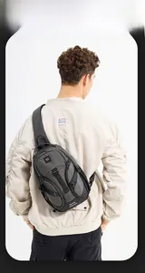 Detail view of a dark grey crossbody bag on a male model back with reflective strip
