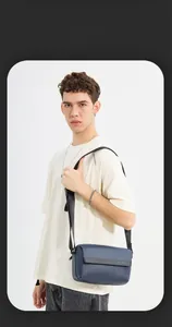 Deep blue minimalist crossbody bag for men shown on model with adjustable strap and front flap