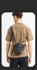 Detail of compact black nylon messenger bag featuring brand logo and adjustable strap