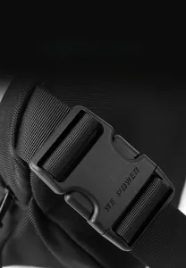 Detail of durable black plastic buckle with embossed logo on woven nylon chest bag strap