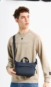 Detail of navy blue nylon chest bag with black adjustable strap on khaki sweatshirt