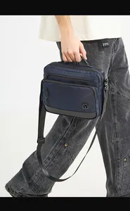 Detail of navy blue waterproof nylon crossbody bag with zipper pockets and handle