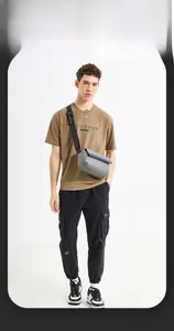 Detail view of grey crossbody bag with adjustable tactical strap worn by male model