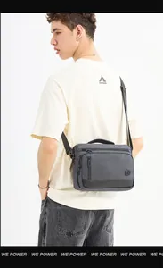 Detail view of dark grey nylon crossbody bag with multiple zip pockets and wide strap