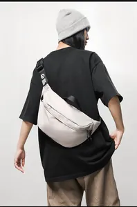 Detail view of a cream-colored crescent chest bag with adjustable black wide strap