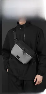 Detail of a grey and black tactical crossbody bag showing zipper and durable fabric