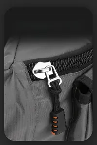Macro detail of silver metal zipper with orange non-slip puller on gray fabric bag