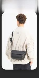 Detailed view of the black leather crossbody bag featuring the logo on an adjustable strap