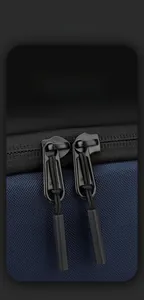 Macro shot of dual zippers with cord pulls on a durable two-tone nylon sling bag