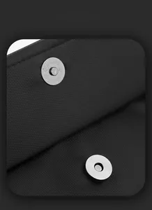 Macro shot of silver magnetic snap closure on textured black crossbody bag fabric