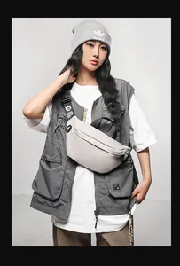 Detail of light grey nylon sling bag with adjustable logo strap and zipper closure