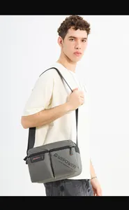 Detail of grey men's crossbody bag featuring reinforced stitching and metal hardware