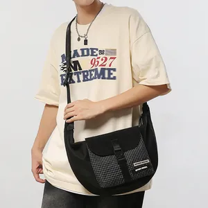 Unisex black half-moon crossbody bag with plaid pocket and buckle detail on beige t-shirt