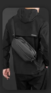 Rear view of a black waterproof crossbody chest bag worn by a model in a minimal urban style