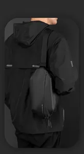 Close-up of matte black waterproof sling bag with geometric tech design on male model