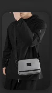 Détail de la sacoche grise avec patch noir portée sur une veste technique moderne