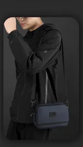 Détail du sac bandoulière en nylon bleu foncé avec double fermeture éclair et logo