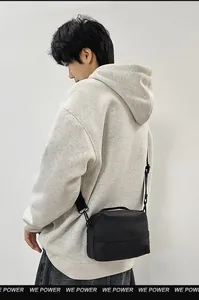 Detailopname van een zwarte waterdichte crossbodytas gedragen door een model in urban stijl