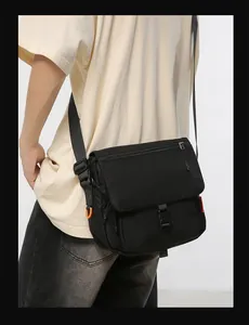 Detail of black techwear messenger bag featuring durable nylon fabric and orange side loop