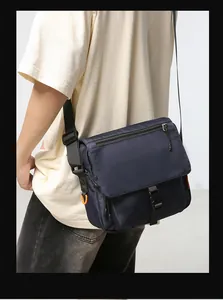 Detail of dark blue nylon messenger bag with buckle closure and orange D-ring accent
