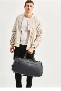 Uomo che trasporta un borsone grigio scuro capiente per viaggi o palestra