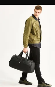 Modello maschile con grande borsa da viaggio nera impermeabile con manici rinforzati e logo