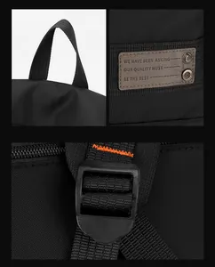 Detail of durable handle, brand tag with rivets, and orange contrast stitching on backpack