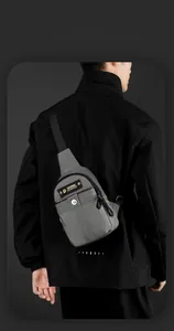 Detail view of water-resistant gray crossbody bag with zipper pocket and brand logo