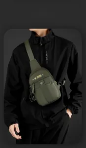 Detail of army green nylon crossbody bag showing multiple pockets and metal hardware