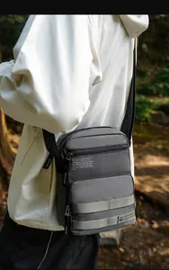 Outdoor-Aufnahme eines Herren in grauer Nylon-Umhängetasche mit mehreren Reißverschlüssen