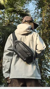 Détail de la texture d'un sac de poitrine noir en nylon porté en extérieur par un mannequin