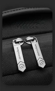 Detail of smooth gunmetal dual zippers with engraved logo on black waterproof backpack