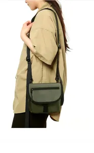 Detail view of olive green nylon crossbody bag with adjustable strap and front zipper
