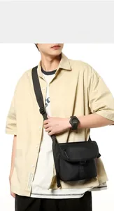 Detailed view of black nylon messenger bag worn with adjustable strap over the shoulder