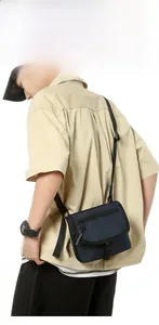 Macro shot of navy blue nylon crossbody bag featuring flap cover and adjustable strap