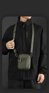 Detail view of an olive green nylon tactical crossbody bag worn by a male model