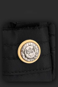 Close-up of black nylon fabric texture and circular metallic star emblem on messenger bag