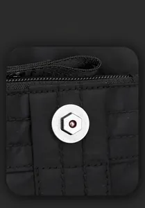 Macro detail of silver magnetic metal buckle on black heavy-duty nylon shoulder bag